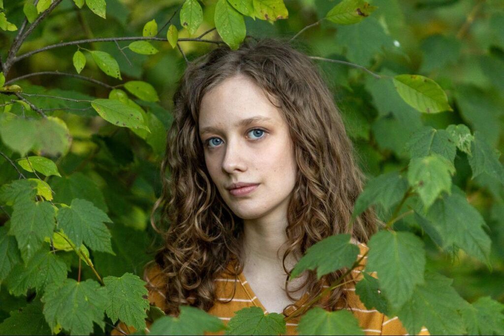 woman looking through leaves